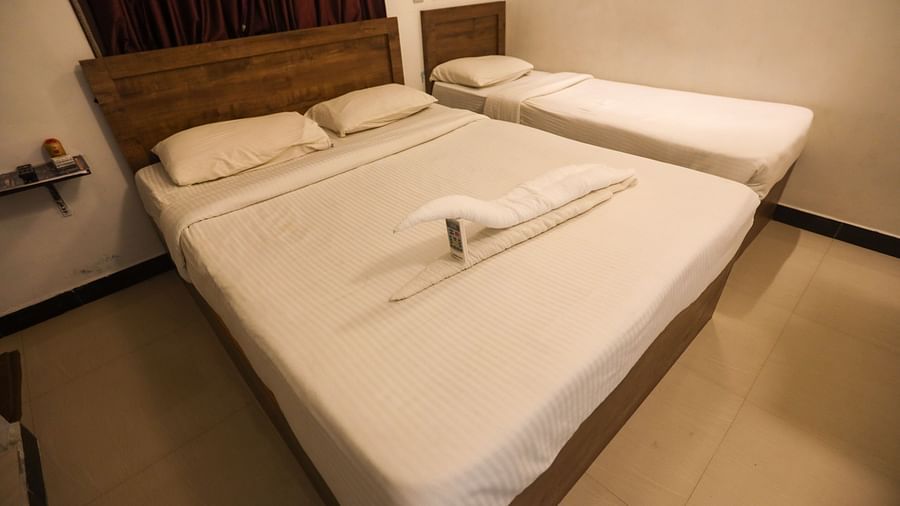 A corner view of a triple bed room with plushy bed and shelves and a wall  at La  Paradise Residency , Pondicherry