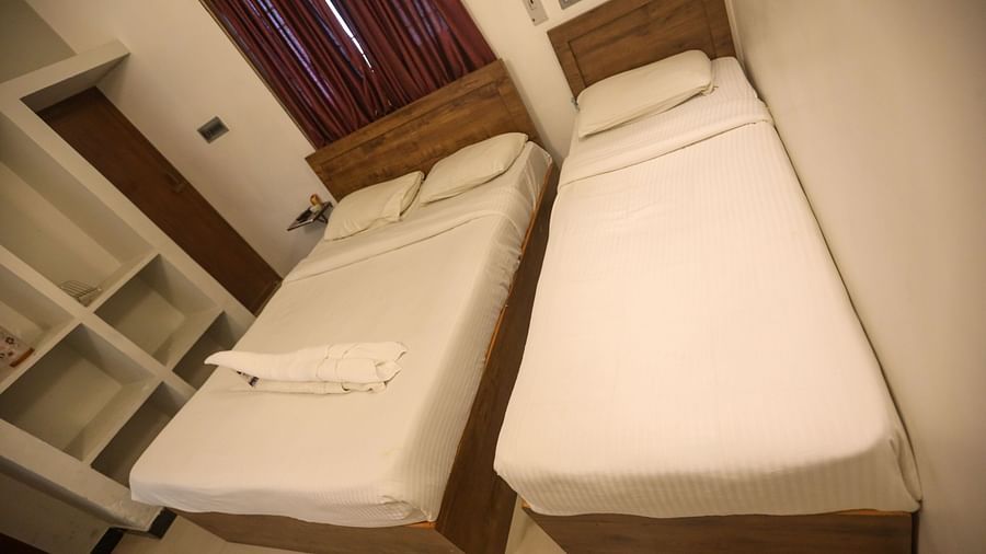 A corner view of a triple bed room with plushy bed and shelves and a wall  at La  Paradise Residency , Pondicherry