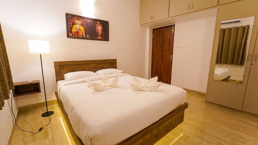 A cosy double bed with a side lamp and a painting above the bed inside Three Bedroom Villa - La Tamara Luxury, Pondicherry
