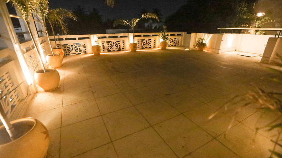 A wide angle view of the terrace during the night time and the terrace decorated with plant and light at The steps from the terrace leading down to the villa covered in red oxide - La Villa Heritage, Pondicherry