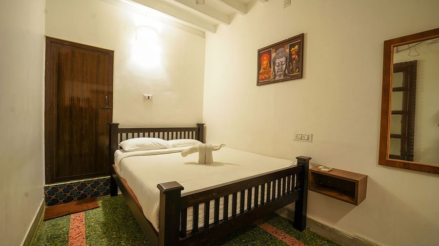 A double bed with a painting hung above next to it and a mirror as well inside Superior Villa - La Villa Heritage, Pondicherry
