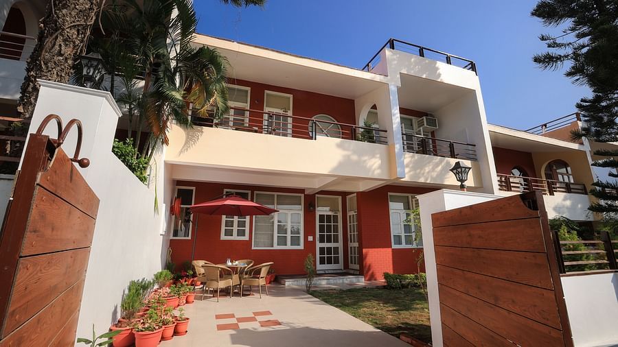 A facade image of a two storey building surrounded by trees and have a few flower pots beside the entrance pathway - Lamrin Boutique Cottages Rishikesh