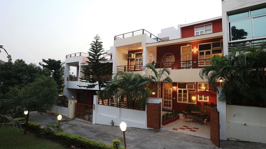 A facade image of a two storey building surrounded by trees and there are also lights beside the pathway to the entrance gate - Lamrin Boutique Cottages Rishikesh