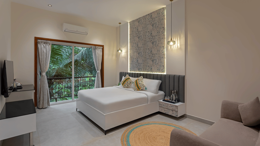 Deluxe room with king bed and large glass doors opening to a garden view at Lamrin Morjim Goa.