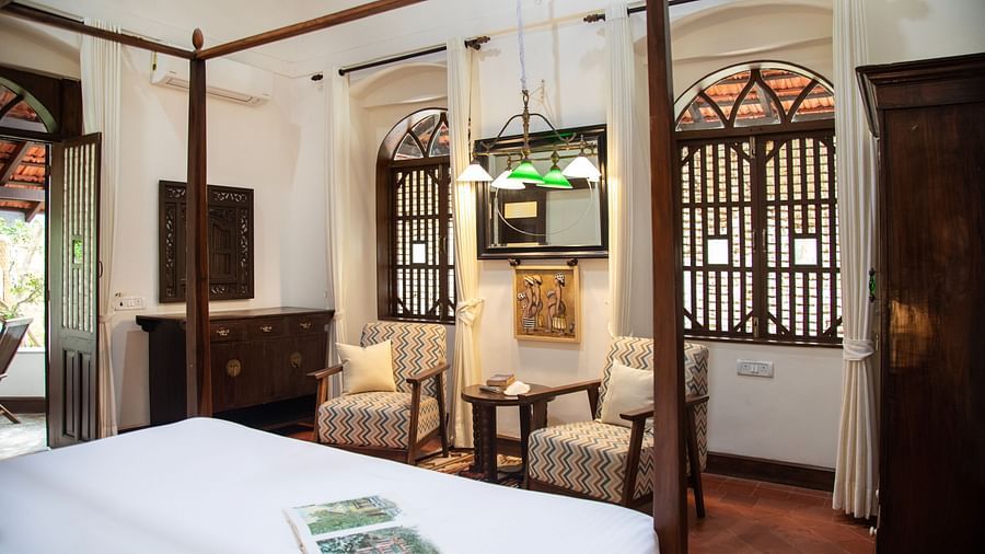 An image of a bedroom featuring a bed, a wardrobe, a work desk and chair, and two vintage styel windowds - Lamrin Ucassaim Hotel, Goa