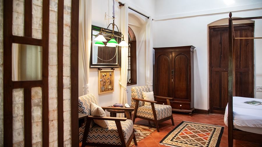 An image of sneak peak of a room faturing two wooden chairs,  wardrobe, and other wooden furnishings at Lamrin Ucassaim Hotel, Goa