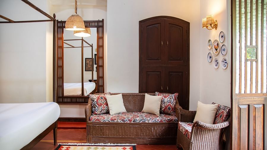An image of a bed with sofa and wooden doors and hanging lights  at Lamrin Ucassaim Hotel, Goa