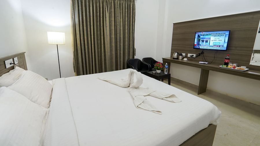 A double bed with a tv wall mounted opposite it inside Double Deluxe Room - Le Poshe Beachview Pondicherry