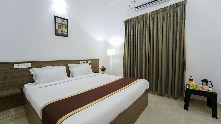 A double bed with side lamps, curtains on the window and an AC inside Deluxe Seaview Double Room - Le Poshe Beachview Pondicherry