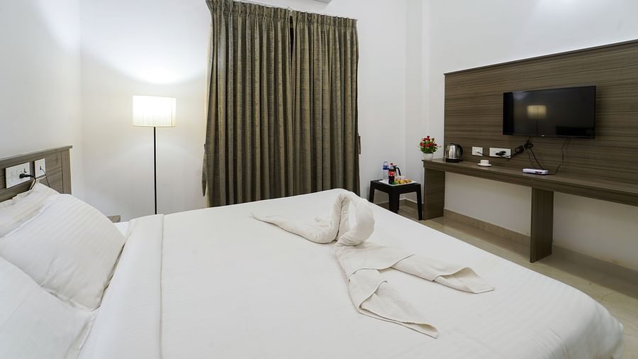 A double bed with side lamps, tv opposite the bed and an AC inside Deluxe Seaview Double Room - Le Poshe Beachview Pondicherry