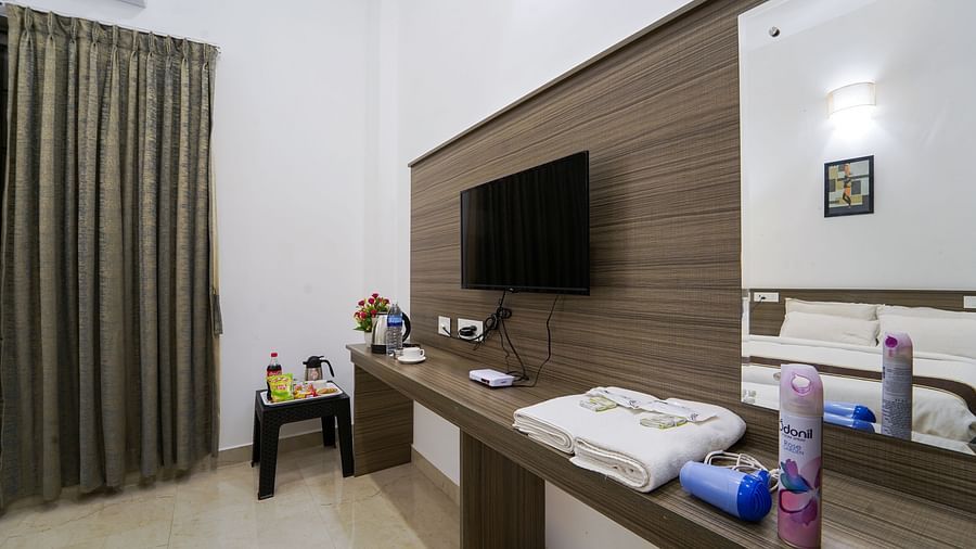 A wall mounted tv with a small table below it and a mirror next to it inside Deluxe Seaview Double Room - Le Poshe Beachview Pondicherry