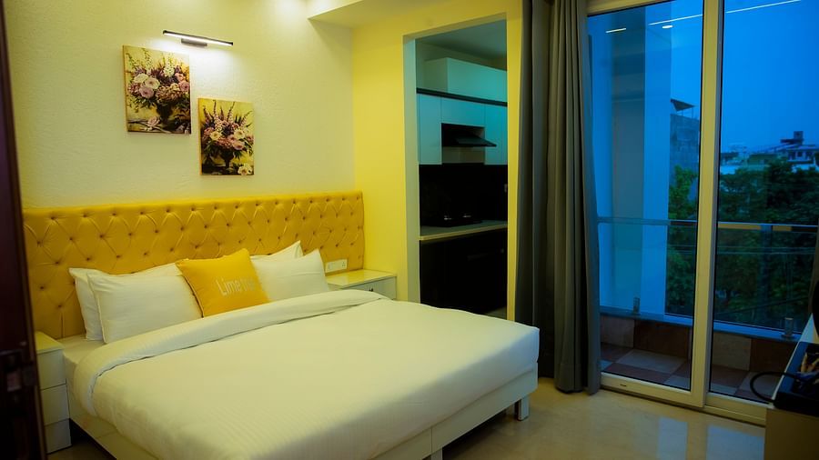 An image of a bedroom with king size bed, photo frames hanged on the wall, and glass door  leading to the balcony - Lime Tree Luxury Studio