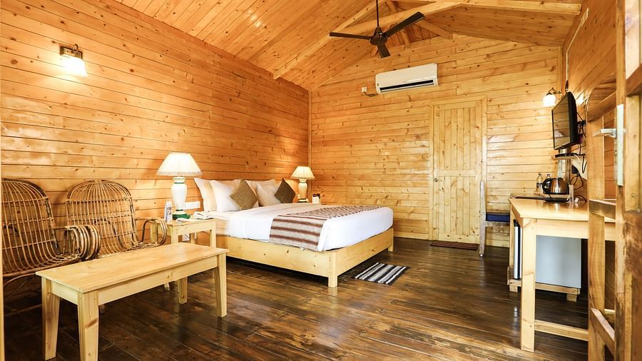 A cosy Deluxe Cottage with plushy bed, table , chairs and TV at Lotus Eco Resort 