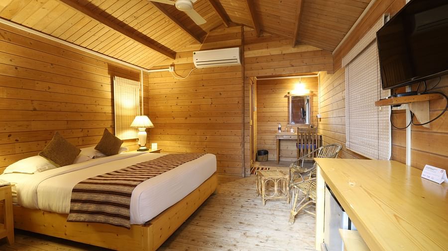 A view of bed room with wooden furnish and Tv, lamp and plushy bed- lotus Eco Beach Resort Konark