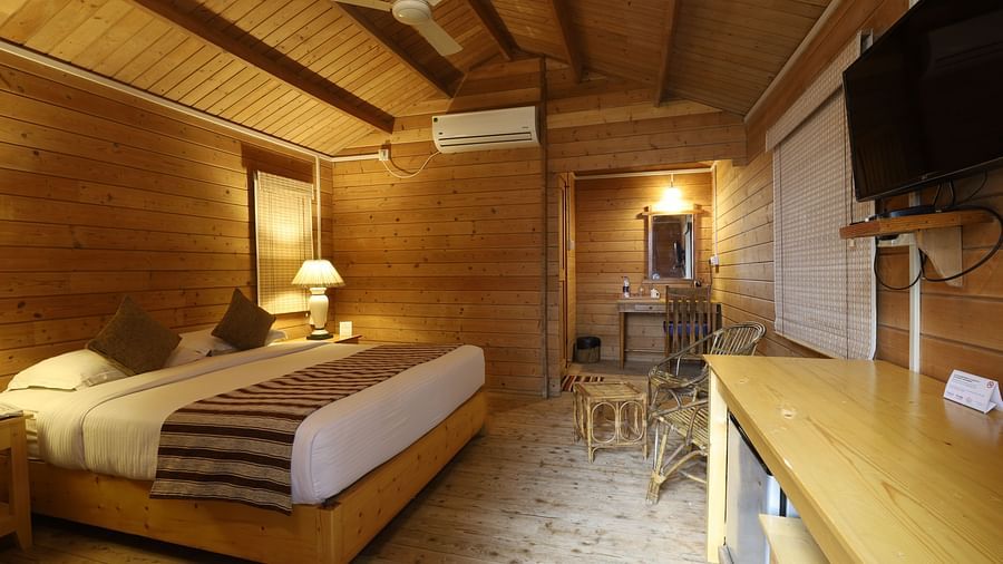 A view of bed room with wooden furnish and Tv, lamp and plushy bed- lotus Eco Beach Resort Konark