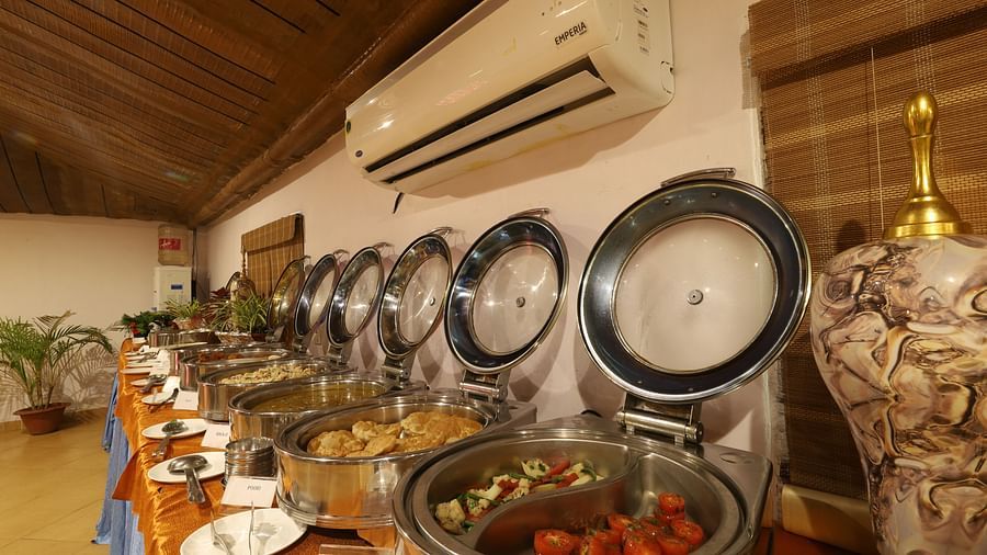 A buffet setup with a variety of dishes presented in metal containers, ready for service, in a dining room with warm lighting- Lotus Eco Beach Resort, Konark.
