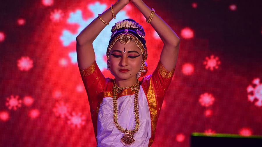A lady wearing a saree and ornaments joining her hands in a prayer posture