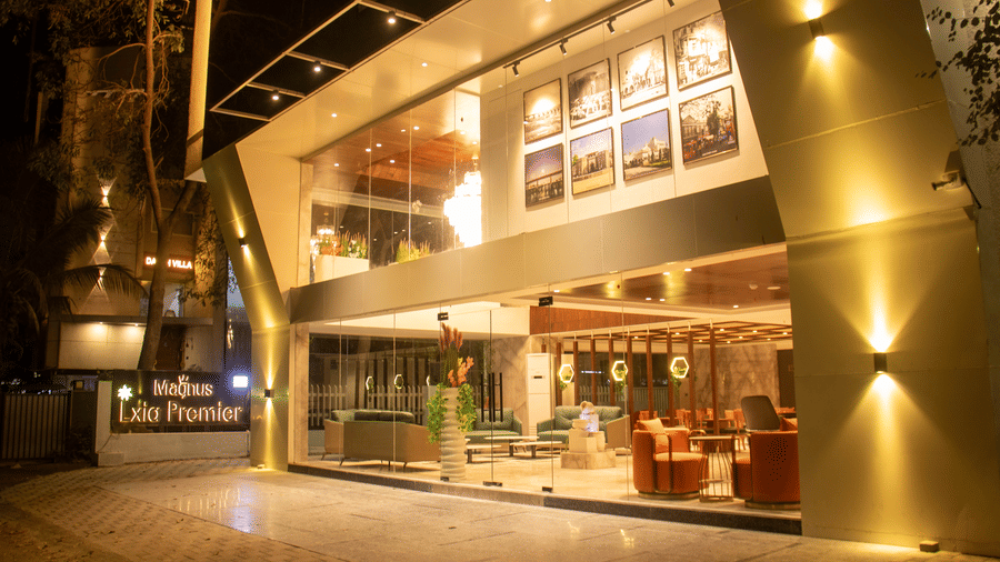 The exterior view of the illuminated entrance and glass facade at Magnus Lxia Premier, Kalyani Nagar at night.