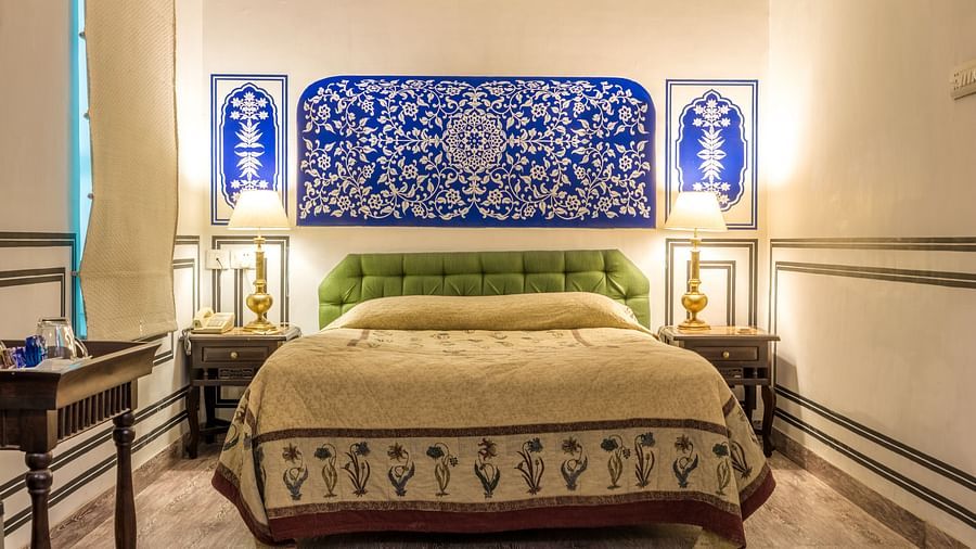 A king bed with lamps on the side table inside deluxe rooms - Mandawa Haveli, Jaipur