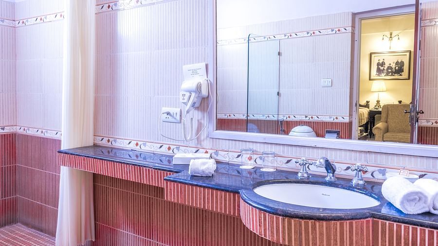 Overview of the bathroom with a mirror and sink in view inside Standard rooms - Mandawa Haveli, Jaipur
