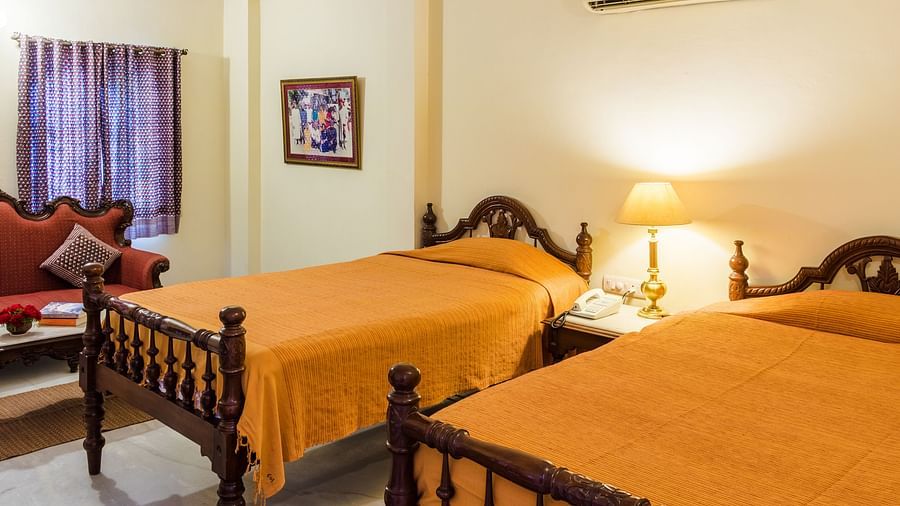 Twin beds with a lamp on a side table in the centre inside Standard rooms - Mandawa Haveli, Jaipur