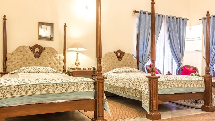 Two twin beds with a lamp on the side table inside deluxe rooms - Mandawa Haveli, Jaipur 