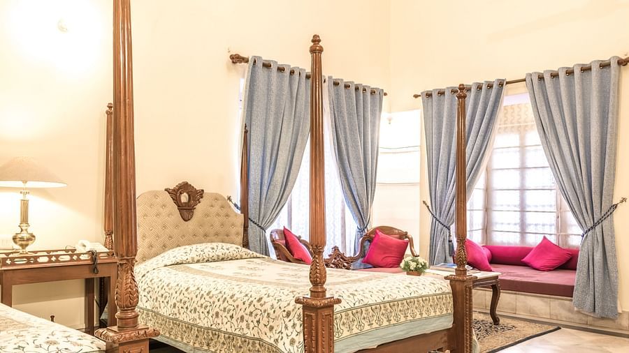 Two twin beds with a seating arrangement on the window sill inside deluxe rooms - Mandawa Haveli, Jaipur 