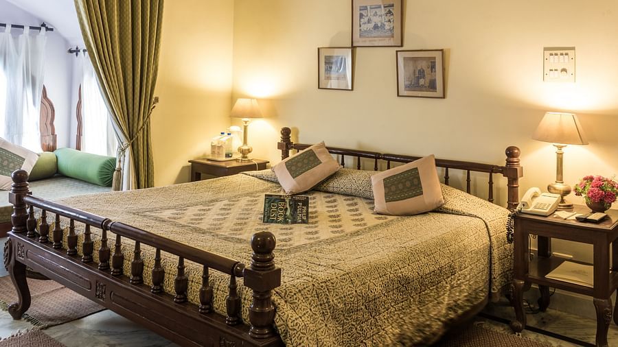 a king bed with lamps on side tables and a sofa next to the bed inside Standard rooms - Mandawa Haveli, Jaipur