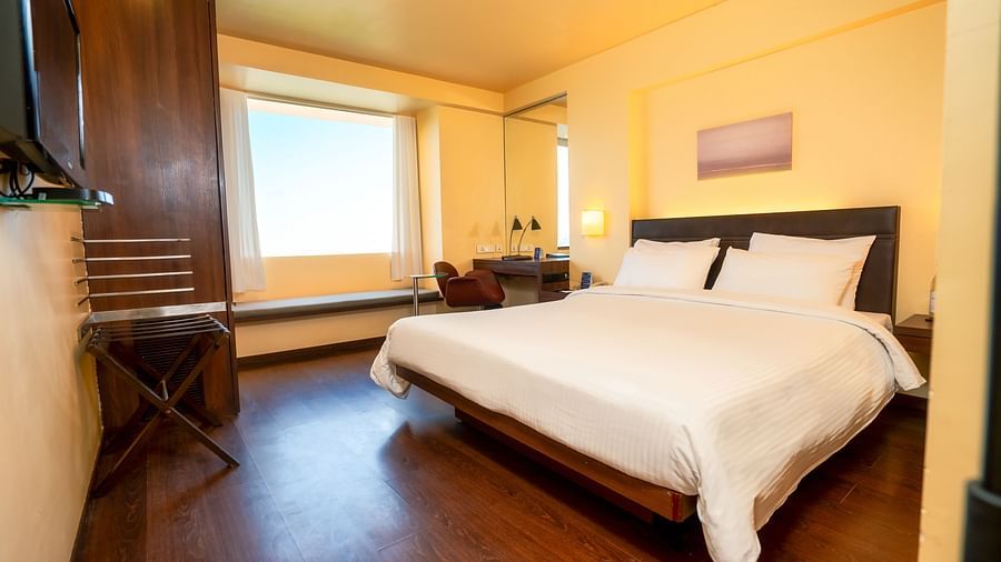 A front view off the suite  with plushy bed and a window with a wall painting  at Marasa Sarovar Portico, Rajkot