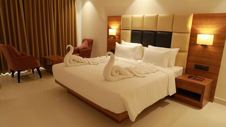 An image a bedroom with a king size bed and on top two swans are made out of towels - Mastiff Grand, Dharwad