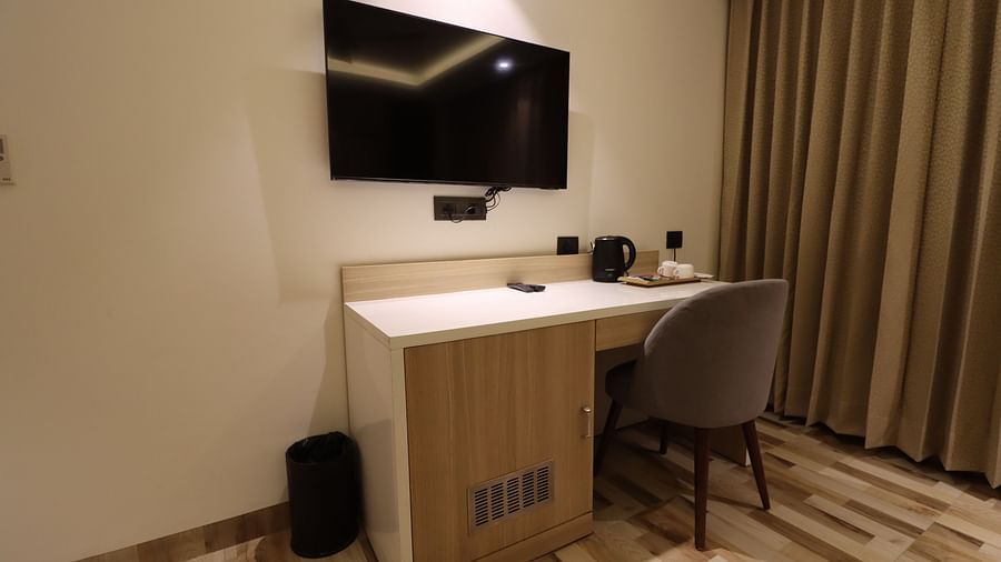 Side view of study table with chair and TV, small dustbin on the side of the Deluxe Room  - Mastiff Hotel, Dhanbad 