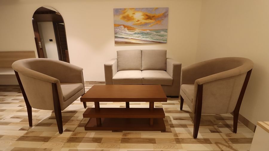 Front view of the Studio Living Room area with sofa set and a coffee table and mirror at the  corner - Mastiff Hotel, Dhanbad