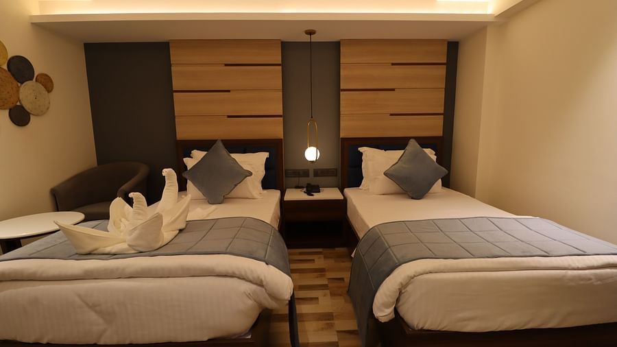 Front view of plush twin beds in Superior Twin with bedside table and illuminating lamp placed between the beds - Mastiff Hotel, Dhanbad 