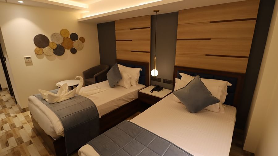 Twin beds with bedside table and wooden interior design in Superior Twin room - Mastiff Hotel, Dhanbad