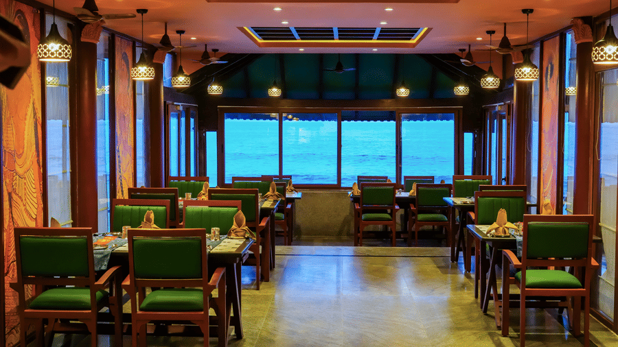 Elegant indoor dining space at MGM Beach Resorts with wooden furniture, ceiling lights, and large windows offering sea views.