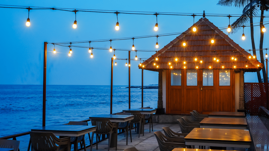 Seaside dining deck at MGM Beach Resorts with string lights and a wooden pavilion overlooking the ocean during twilight.