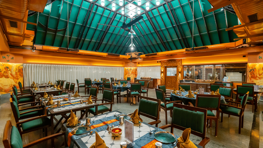 Indoor restaurant at MGM Beach Resorts featuring wooden interiors, green roofing, and neatly arranged dining tables set for guests.