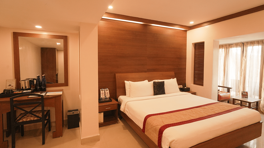A room with a neatly arranged bed with good lighting and a desk and chair arranged in the side.