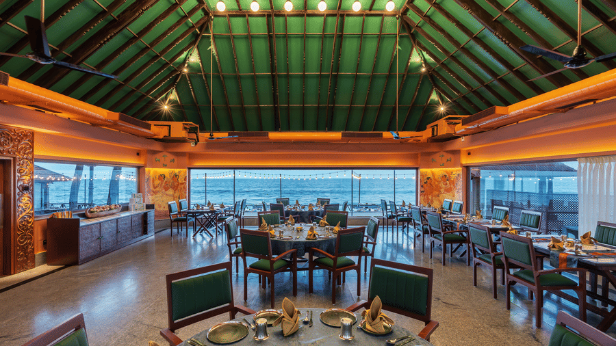 Spacious restaurant interior at MGM Beach Resorts with a green-tinted glass roof and panoramic beach side windows.