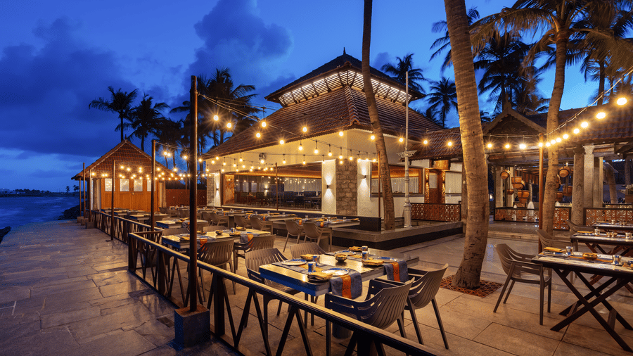 Illuminated outdoor dining setup by the sea at MGM Hotels & Resorts, with tables and chairs set for dining.
