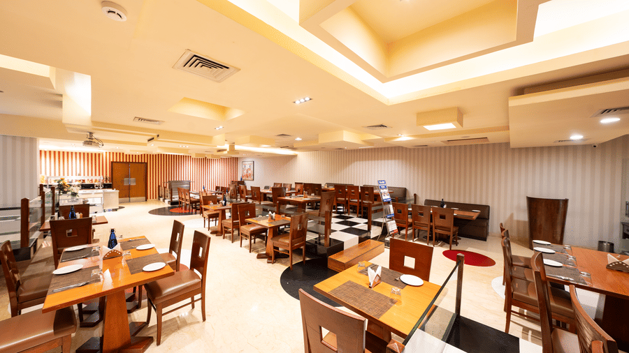 A dining space at MGM Mark Whitefield, featuring chairs, tables, and checkered wall.