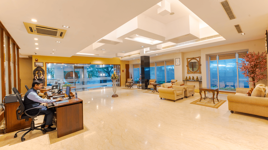 The reception desk with receptionists at MGM Mark Whitefield, featuring sofas, elongated desk, and lights.
