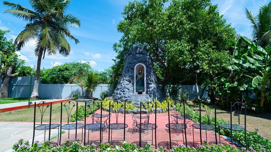 Image of an idol of Mother mary holding baby Jesus and open-air seating arrangements in front of them