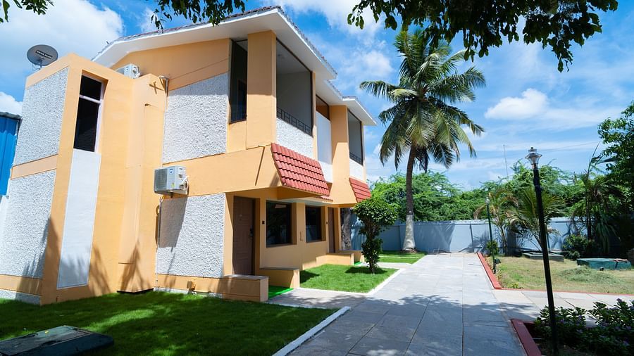 Image of a two-storey building painted in coral and white with pavements in front of it on a sunny day