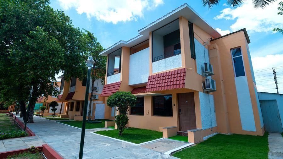 Image of the facade of hotel rooms featuring lawns beside the pavements under a grey-blue sky