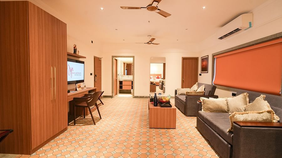 Image of the living room featuring two sofa-cum-beds facing the TV in front and a coffee table with food and beverages on it and a 