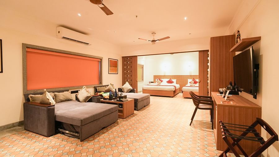 Image featuring a partition between the living room and bedroom featuring sofa-cum-beds in living room facing the TV and double bed and a single bed in the bedroom