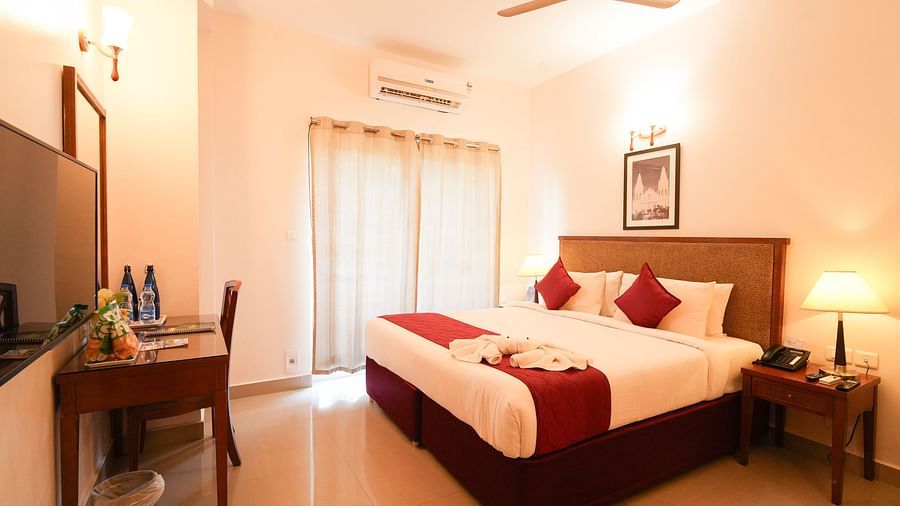 Grandeur Room displaying a plush bed with a nightstand next to it and a TV in front