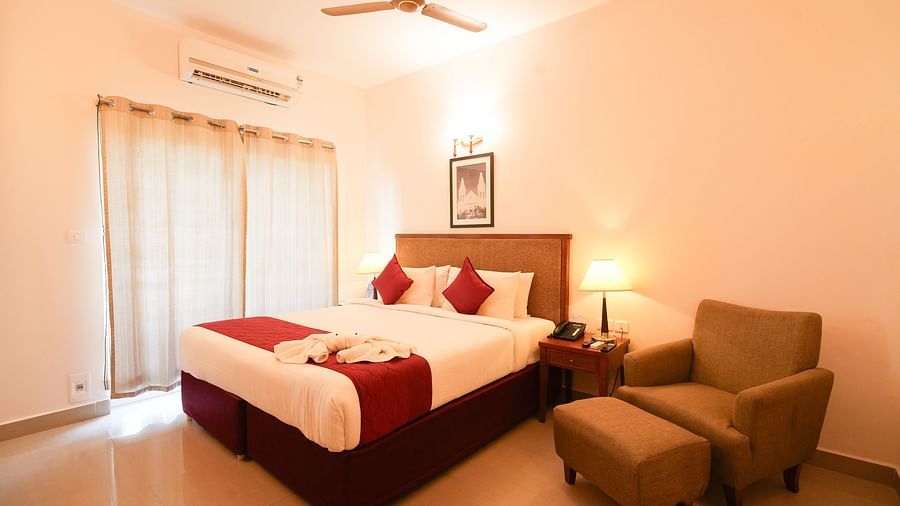 Grandeur Room featuring a plush bed and a couch with ottoman next to the nighstand