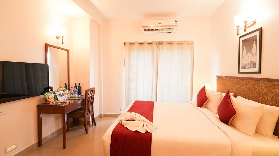 Image of Grandeur Room featuring a plush bed facing the TV mounted on the wall